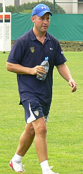 Alex King caminando con una botella de agua de plástico en su mano derecha durante una sesión de entrenamiento para un partido de rugby