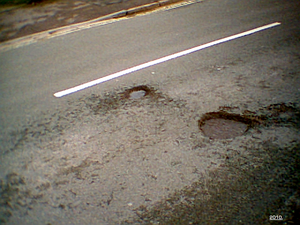 Small potholes, showing isolated failures of the pavement and its subsurface structure, in a road in Banbury, UK