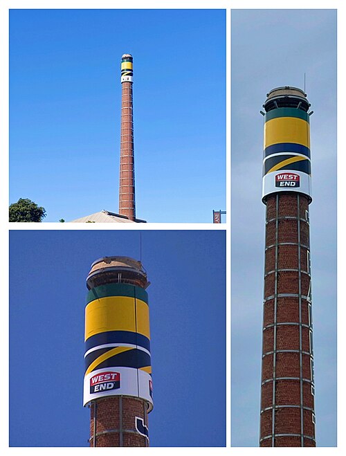The kiln chimney with the Woodville West Torrens Eagles blue, green and gold colours aloft as 2021 SANFL premiers, above the Glenelg Tigers' black and