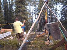 Lifting a heavy timber with a block and tackle on a tripod. Building a cabin in forest.jpg