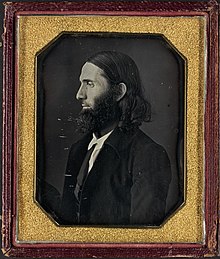 side-facing portrait of Burleigh a man with long hair and a long chin bears