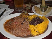 Ropa vieja (shredded flank steak in a tomato sauce base) with black beans, yellow rice, plantains and fried cassava Cubanfood.jpg