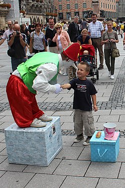 Young child is entertained by a street performer in Marienplatz, Munich, while crowd watches.