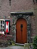 Natuurstenen poortje met beeldhouwwerk, oorspronkelijk behorende bij de Haveloozenschool