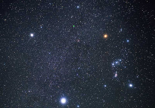 Sirius (bottom) and the constellation Orion (right). The three brightest stars in this image—Sirius, Betelgeuse (top right) and Procyon (top left)—form the Winter Triangle. The bright star at top center is Alhena, which forms a cross-shaped asterism with the Winter Triangle.