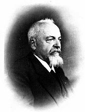 fotografie de profil cu trei sferturi a unui bărbat, purtând barba albă și mustață