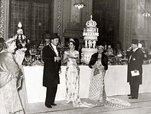 A banquet organised on the occasion of the wedding of King Farouk I and Queen Farida of Egypt. The persons appearing in the photograph are (from left to right):
Princess Nimet Mouhtar (1876-1945), Farouk's paternal aunt;
King Farouk I (1920-1965), the groom;
Queen Farida (1921-1988), the bride;
Sultana Melek (1869-1956), widow of Hussein Kamel, Farouk's paternal uncle;
Prince Muhammad Ali Ibrahim (1900-1977), Farouk's 2nd cousin once removed. ModernEgypt, Farouk & Farida Marriage, DHP13655-20-9 01.jpg