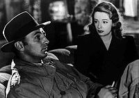 Nigra kaj blanka ekranpafo de Robert Mitchum maldekstre kaj Jane Greer sur la rekte en la filmo El la Pasinteco