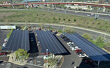 Solar canopy parking lot in New Haven at Hotel Marcel. There are EV level 2 chargers underneath the canopy and a 12-stall Tesla Supercharger behind. Parking under Solar Canopy (52937580768).jpg