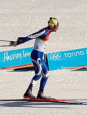 Foto van een langlaufer in een blauwe jumpsuit en met een bril op.