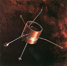 Une sonde spatiale en forme de tonneau avec plusieurs antennes flotte dans l'espace rouge-noir.