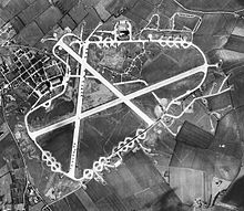 Aerial photograph of the airfield, 2 March 1944. The technical site with two T2 hangars are at the left (west). There are three more T2 hangars and the bomb dump north of the perimeter track. A large number of aircraft are parked on the north/south crosswind runway and on the hardstand loops around the perimeter track