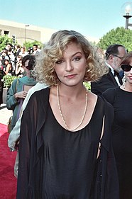 A blonde woman in a black dress looking at the camera