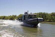 A medium-sized boat leaving a wake as it travels through murky waters