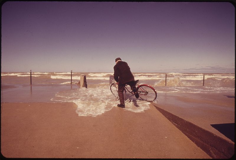 File:WAVE CRASHES OVER SEAWALL, TAKING AN ELDERLY BICYCLE RIDER BY SURPRISE - NARA - 547158.jpg