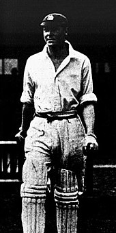 A cricketer leaving the pavilion holding a bat