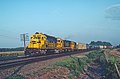 AT&SF 5159 an early morning eastbound just west of the Merrick crossover plant W of Emporia, KS in August 1983 (28345404874).jpg