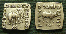 The front and back of a silver colored square coin side by side.  One side shows an elephant, the other a buffalo