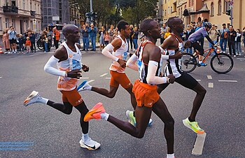 Winner Eliud Kipchoge (left) about 25 km (16 mi) into the race, behind pacemakers (in striped gear) and alongside Derseh Kindie (center midground), who did not finish the race Berlin-Marathon 2023 Eliud Kipchoge bei Kilometer 25 A.jpg