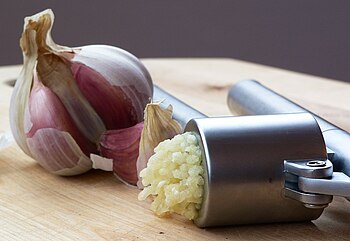 An Ikea garlic press, with pressed garlic.