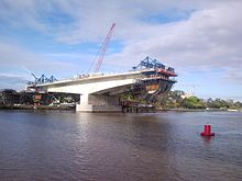 Uma seção em forma de T da ponte sendo construída sobre um rio