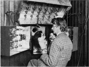Baird in 1925 with his televisor equipment and dummies "James" and "Stooky Bill" (right). John Logie Baird and Stooky Bill.png
