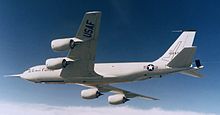 A KC-135 aircraft faces the left of the image, shown from the bottom. All four CFM56 engines are visible hanging in their nacelles on the underside of the wing.