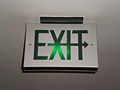 Metal exit sign with green text and permanent directional arrow