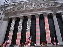 The columns of the NYSE lit up for Christmas, with the American flag being projected onto the colonnade