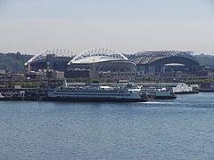 Lumen Field and T-Mobile Park seen from Pier 66, 2009. The now-demolished shed of Pier 48 can be seen to the right of the ferries at Colman Dock.