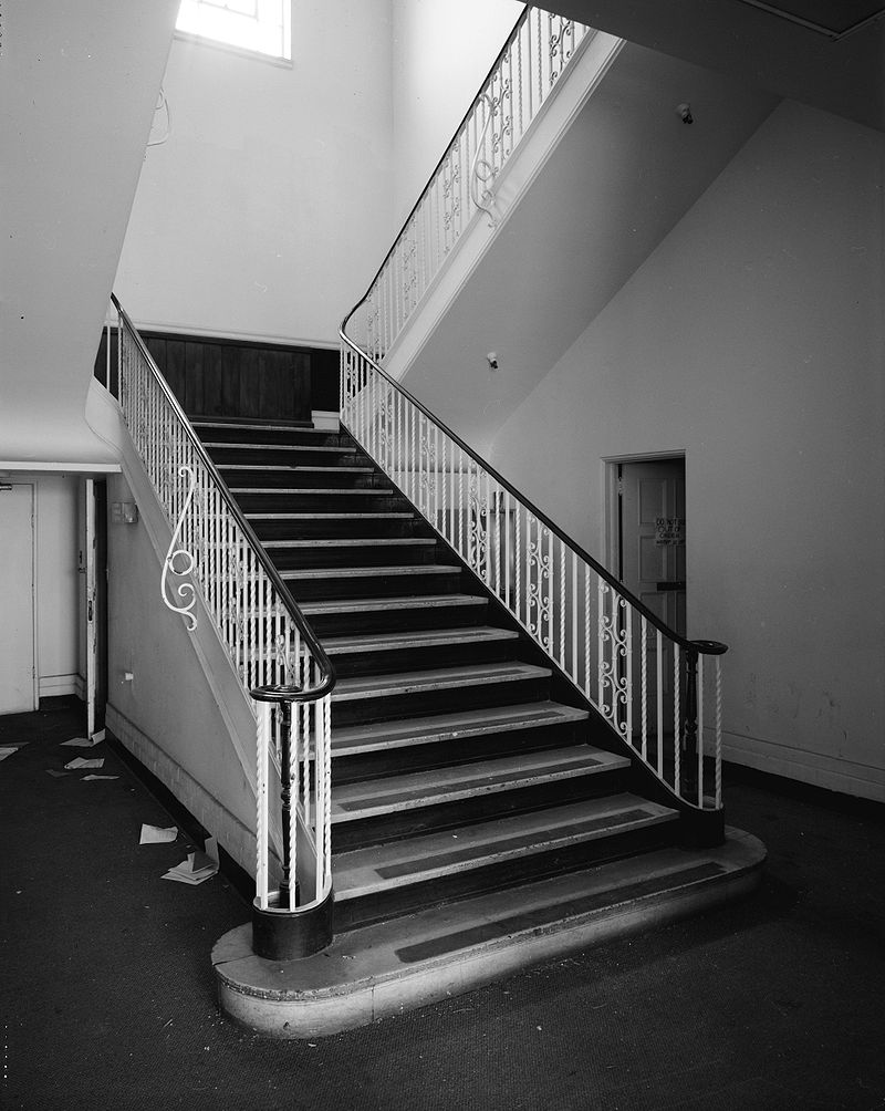 a black and white image of a staircase with a filigree banister