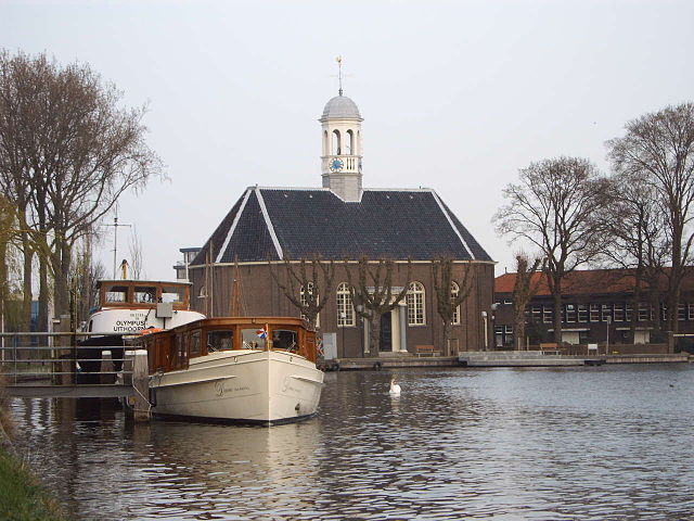 Een kerk aan het water met in de voorgrond een paar bootjes