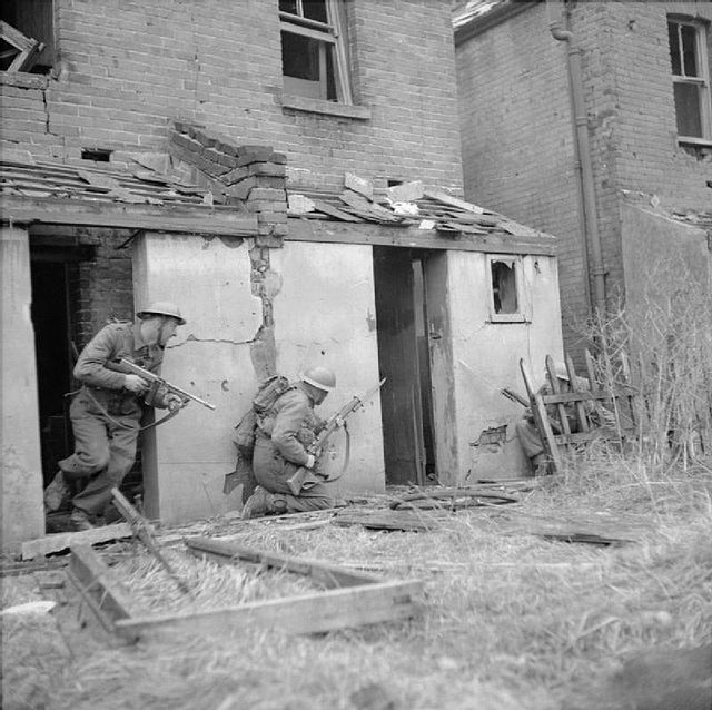 Soldiers at the division's battle school; bomb-damaged houses are being used to provide a realistic training environment for fighting in built-up area