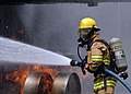 En befalshavende i den japanske marinens brannvesen slukker en brann på en flykropp-modell under en øvelse.