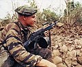 Un membre des Navy SEAL au Vietnam tient sa mitrailleuse légère Stoner 63 prête pendant que le reste de son équipe prépare des charges de démolition sur un bunker vietnamien. L'arme est équipée d'un conteneur à bande de 150 cartouches et est alimentée par le côté gauche. La poignée de rétraction est verrouillée vers l'avant et l'orifice d'éjection est fermé par un couvercle anti-poussière pour minimiser l'entrée de saletés.