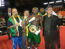 Baru IBO International juara kelas menengah Osumanu Adama (pusat) dengan manajer Wasfi Tolaymat di atas ring di UIC Pavilion di Chicago, oktober 2010