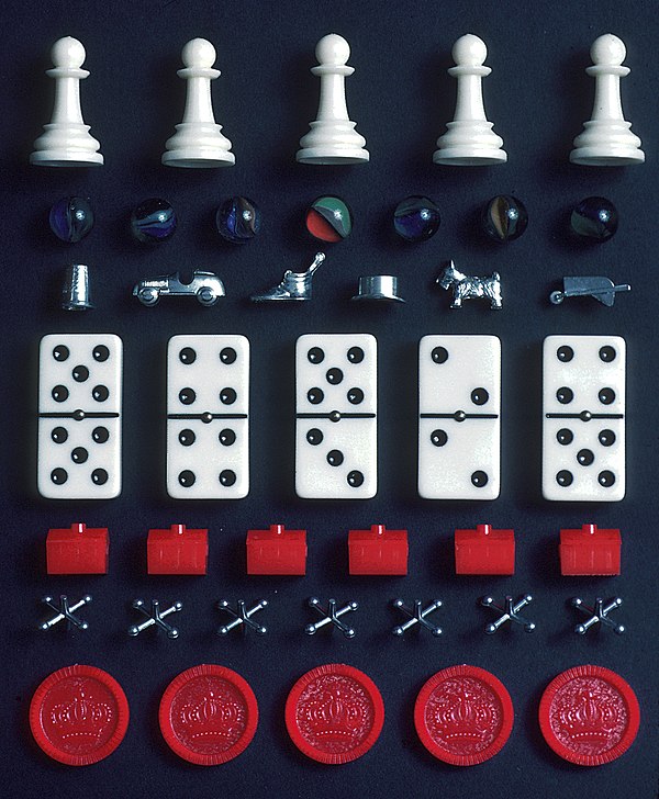 A selection of pieces from different games. From top: Chess pawns, marbles, Monopoly tokens, dominoes, Monopoly hotels, jacks and checkers pieces.