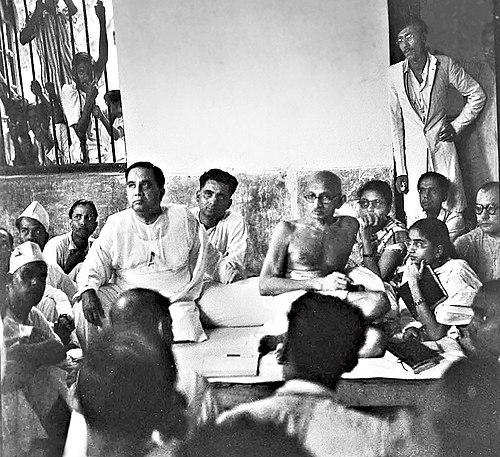 Mujib (standing right) with Mahatma Gandhi (seated center) and H. S. Suhrawardy (seated left) in Noakhali, 1946