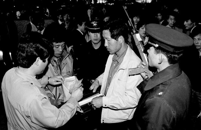 Police inspect an ID card at a checkpoint in 1975.