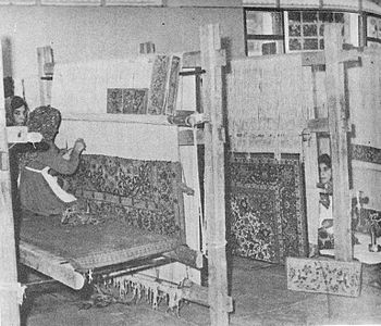 Tabriz looms in a carpet-making school in Iran in 1975. One weaver sits on the floor, two on a bench.