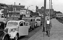 Traffic queueing for the Woolwich Ferry in 1955. The modernisation of the roll-on/roll-off service in 1963 reduced waiting times. London traffic queue geograph-3065636-by-Ben-Brooksbank.jpg