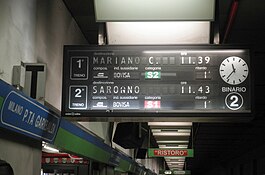 Milano Porta Garibaldi'de, bir sonraki kalkış olarak Mariano Comense'ye giden bir S2 trenini gösteren bölünmüş kanatlı ekran.