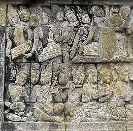 This is an image of an engraving from the ancient Indonesian temples. There are groups of people using the Gendang Melayu.