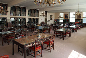 A room filled with many tables and chairs and bookshelves lining the walls.