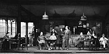 Humphrey Bogart (left) and Leslie Howard (standing center) in the 1935 Broadway stage production of The Petrified Forest, directed by Arthur Hopkins