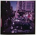 Presidential candidate Dwight Eisenhower sits atop an open convertible in a parade going through a city street.jpg
