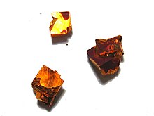 Photograph of three crystals of sodium tungsten bronze