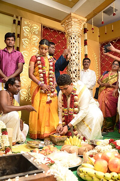Tamil bride and groom performing the ritual of metti anidal