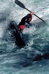 A solo kayak paddler performs a 'high brace' in foamy water. One of the hazards of whitewater paddling is that highly aerated water decreases the effect of buoyancy. WhitewaterKayaking-BLM.jpg