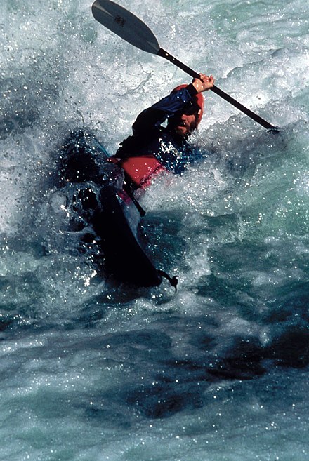 A solo kayak paddler performs a 'high brace' in foamy water. One of the hazards of whitewater paddling is that highly aerated water decreases the effect of buoyancy.
